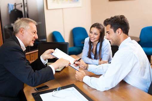 Senior businessman showing a document to sign to a couple