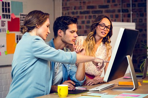 Graphic designers discussing over computer in office